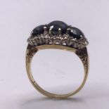 A Three stone sapphire ring set with diamond surround on a Persian (untested) gold mount. Size J