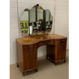 A dressing table flanked each side with cupboards and shaped mirror (H75cm W128cm D57cm)