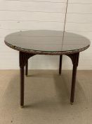 A Vincent Sheppard rattan style Lloyd Loom table with glass top (H75cm Dia90cm)