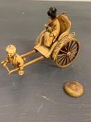 An ivory/resin figure of a boy pulling a rickshaw