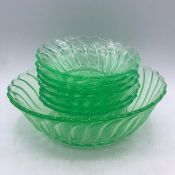 Seven uranium green glass bowls comprising of one larger/serving bowl and six dessert bowls