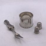 A small selection of silver items to include two thimbles, a napkin ring and fork