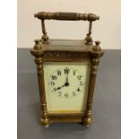 A brass carriage clock with enamel face and column sides