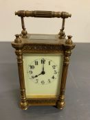 A brass carriage clock with enamel face and column sides