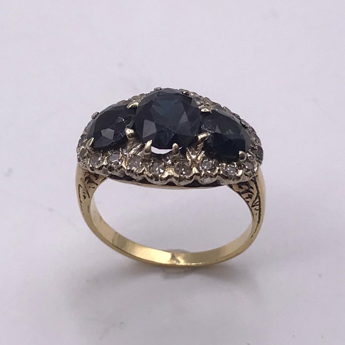 A Three stone sapphire ring set with diamond surround on a Persian (untested) gold mount. Size J - Image 2 of 2