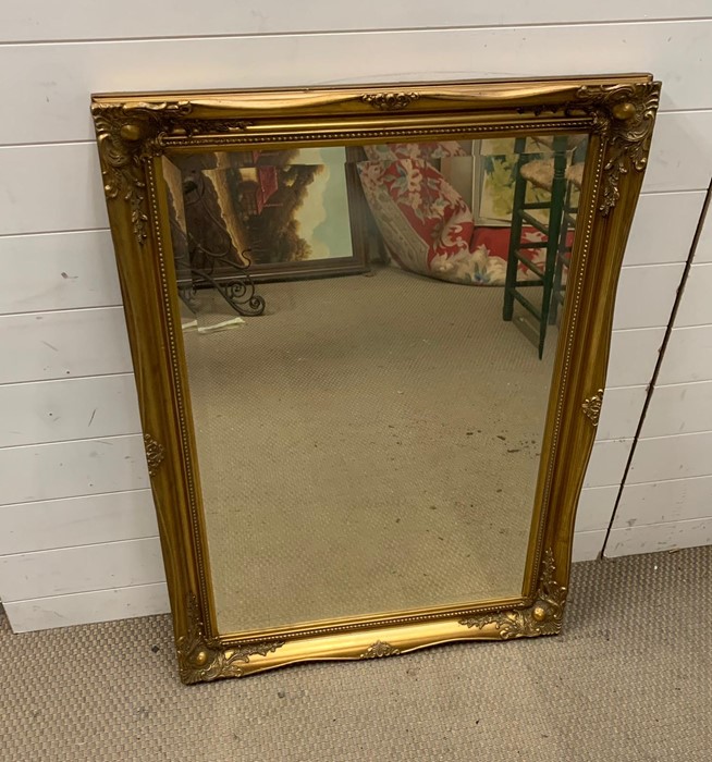 A gilt framed mirror with scrolling swags to corners