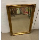 A gilt framed mirror with scrolling swags to corners