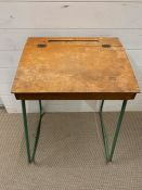 A vintage school desk with green metal legs