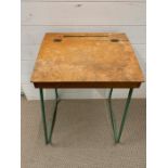 A vintage school desk with green metal legs