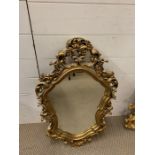 A gilt wall mirror with shaped mirror plate and scrolls (78cm x 43cm)