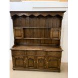 A large oak dresser, with plate rack and small cupboards sat on a base with drawers and cupboards (