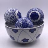 Four blue and white ceramic balls and a bowl