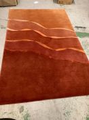 A large hand knotted and made in Nepal red and orange rug with wave design through centre (300cm x