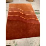 A large hand knotted and made in Nepal red and orange rug with wave design through centre (300cm x