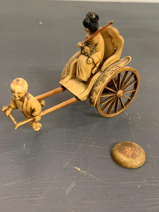 An ivory/resin figure of a boy pulling a rickshaw