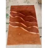 A hand knotted and made in Nepal red and orange rug with wave design through centre (178cm x 120cm)