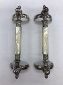 A Pair of decorative knife rests in white metal