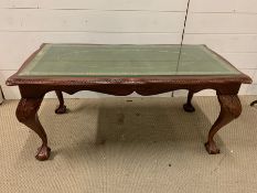 A glass topped coffee table on ball and claw feet (H45cm W97cm D50cm)