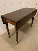 A mahogany hall table with drop sides and turned legs terminating with brass castors