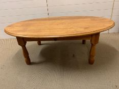 An oval pine coffee table on turn legs (H46cm W135cm D90cm)