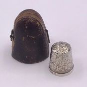 Two collectable thimbles, one hallmarked silver and another in a leather case.