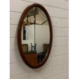 A oval inlaid mahogany mirror (46cm x 72cm)