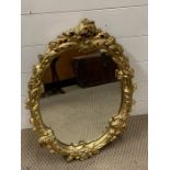 A oval hall mirror in gilt frame with scroll and flower design
