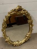 A oval hall mirror in gilt frame with scroll and flower design