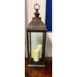 A contemporary hurricane lamp with three electric candles