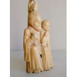 A Meiji period carved ivory okimono of a seated man and woman, 12 cm H