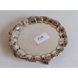 A George V silver salver with pie crust and scallop rim on three scroll feet by Goldsmiths &