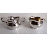 An Art Deco Indian white metal two-handled pouring bowl and matching wavy rim bowl with gilt