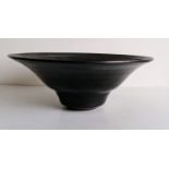 An iridescent black circular bowl, 7 x 18 cm, incised studio stamp to base for Dame Lucie Rie,