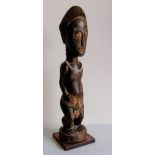 An African carved tribal wood figurine, 34 cm on a later base and a small stone tribal figurine,