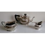 An Edwardian-style three-piece silver plated tea service with half-fluted design, ebony knop and