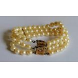 A Chinese three-strand pearl bracelet with a gold clasp, stamped 14k, 19cm