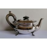 A late Victorian silver bachelor teapot with gadrooned rim, wood knop and handle, on four shell