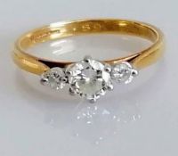 A three-stone diamond ring in a claw setting, the central stone 0.25 carats, on 18ct yellow gold,