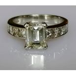 A diamond ring set with a central emerald-cut diamond, weighing a calculated 2.00 carat