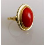 An oval cabochon coral dress ring on a yellow gold setting, coral 15mm x 11mm, size P, stamped