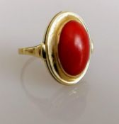 An oval cabochon coral dress ring on a yellow gold setting, coral 15mm x 11mm, size P, stamped