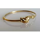 A yellow gold bangle with dolphin decoration, stamped 9kt, 4.33g