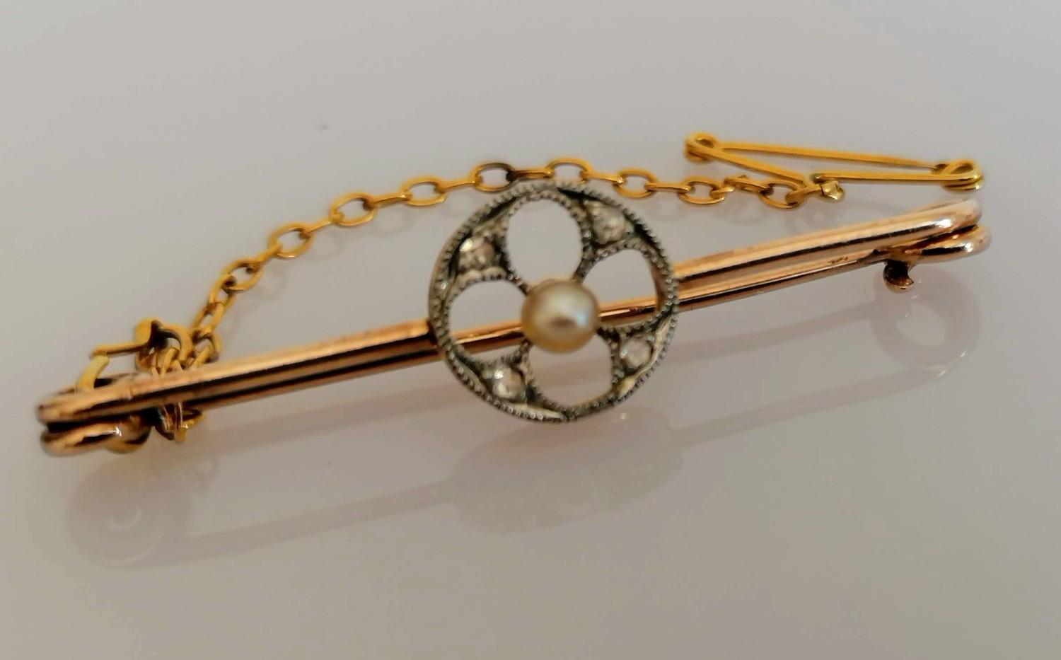 An Edwardian gold brooch with pearl and diamond decoration, safety chain, 4 cm, unmarked but tests