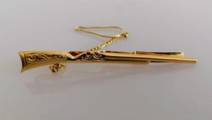 A yellow gold tie clip in the form of a rifle with safety chain, stamped 585, 6 cm, 6.78g