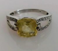 An 18ct white gold gem-set cushion-cut ring with diamond decoration to shoulders, size L, stamped,