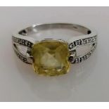 An 18ct white gold gem-set cushion-cut ring with diamond decoration to shoulders, size L, stamped,