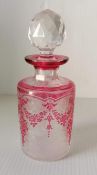 A Val St. Lambert etched cranberry glass cologne bottle with acid-cut rose wreath motif and