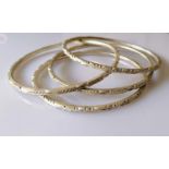 Four Indian silver anklets or bangles with isometric decoration, each 10.5 cm diameter, 239g