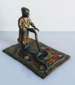 An early 20th Century cold painted bronze depicting a snake charmer and snake on a polychrome carpet