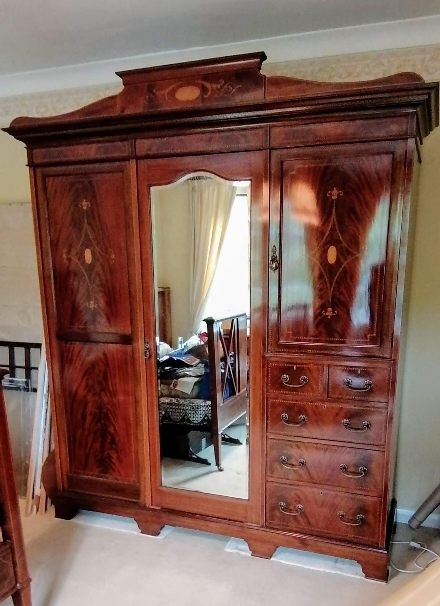 An Edwardian bedroom suite comprising: a treble wardrobe with carved pediment, interior fitted for